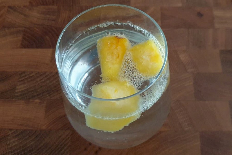 Glas water met bevroren ananasstukjes